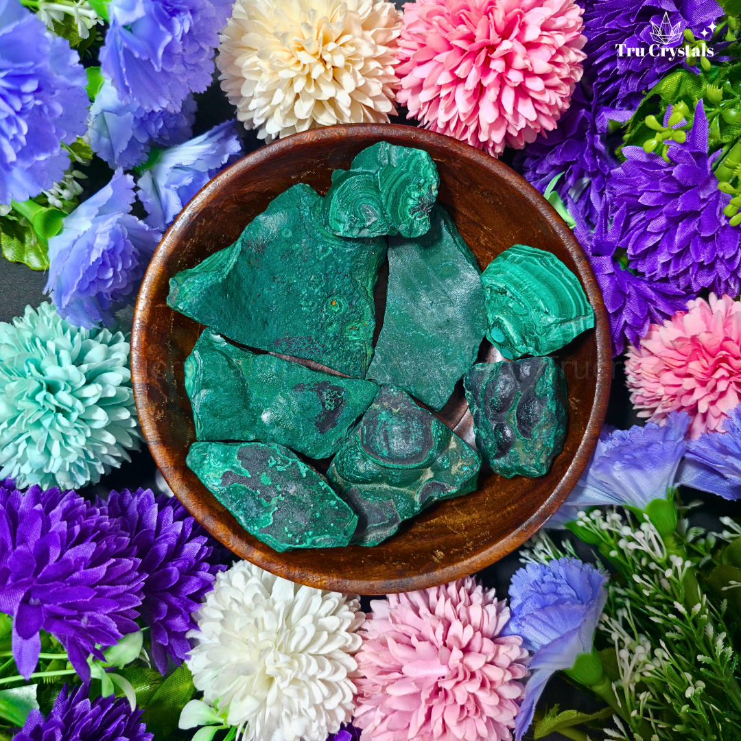 Green Malachite Rough crystals in a wooden bowl surrounded by colorful flowers