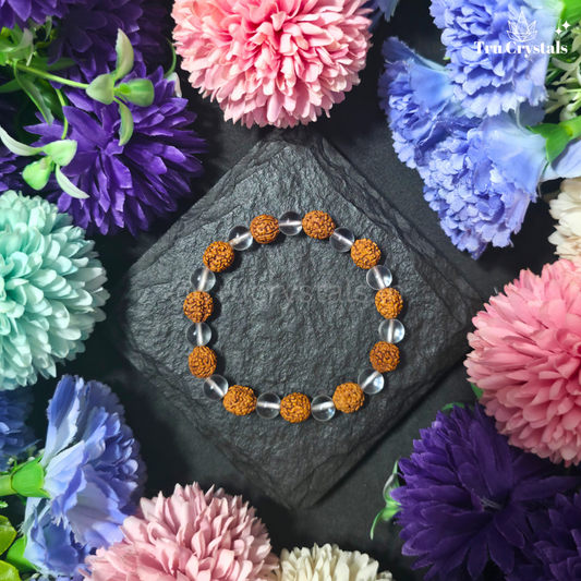 A bracelet with a combination of dark brown (Rudraksh) and clear quartz beads (Sphatik) displayed against a backdrop of colorful flowers.