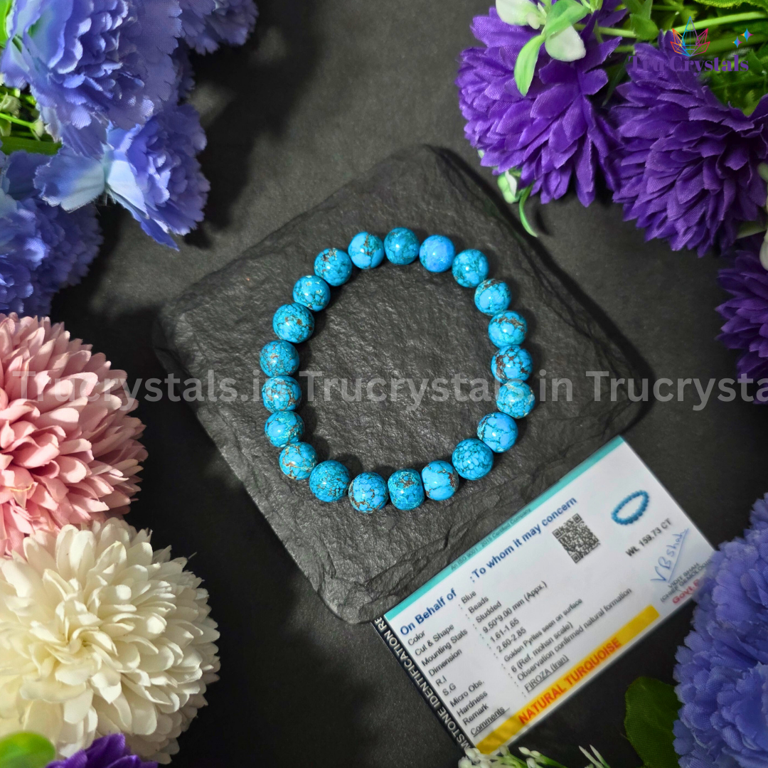 Blue beaded Iranian Turquoise bracelet on a dark stone surface with flowers around