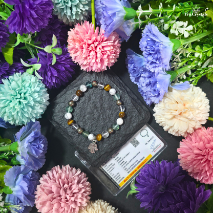 A multicolored student  bracelet featuring Tiger eye , fluorite , howlite,clear quartz and pyrite and a metal charm in the shape of a hand, displayed on a dark stone surface with flowers along with certificate  in the background.