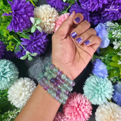 Handmade fluorite gemstone bracelet featuring smooth, polished beads in mixed green and purple tones on an elastic cord.