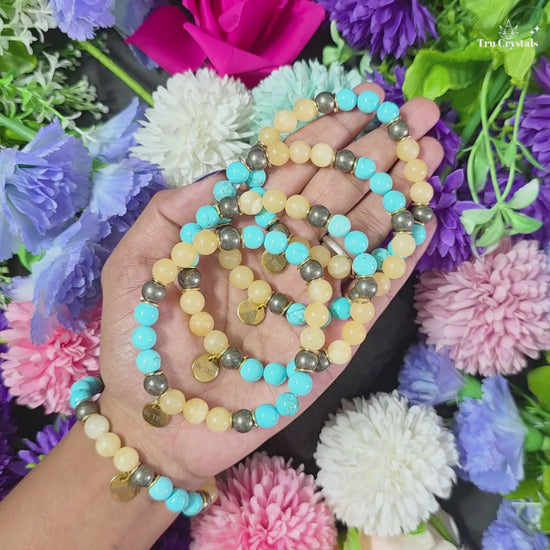 A bracelet for numerology 3 and jupiter containing turquoise, pyrite and yellow calcite with be tru charm with a dark backgroundA bracelet for numerology 3 and jupiter containing turquoise, pyrite and yellow calcite with be tru charm with a dark background