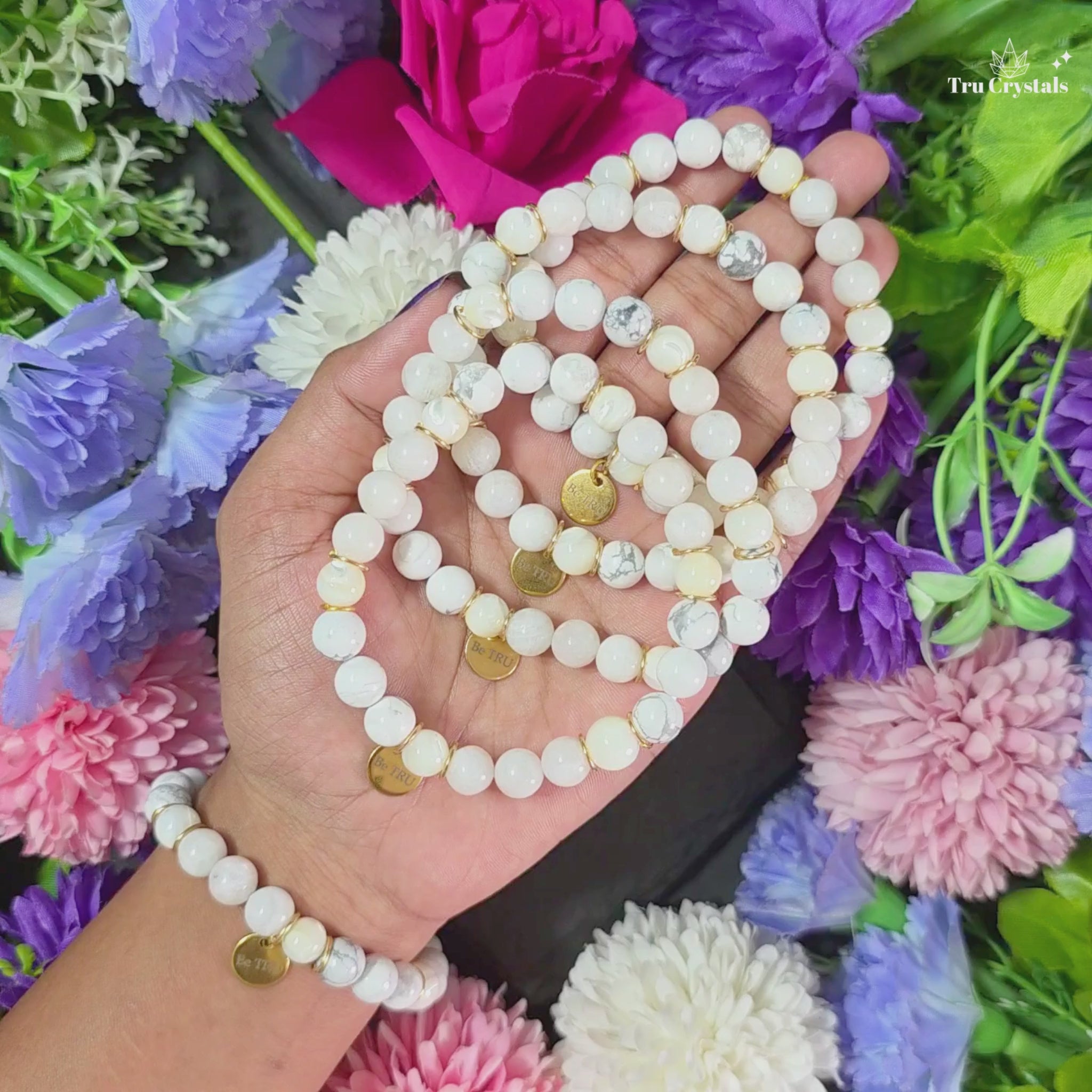 A bracelet conataining moonstone  , howlite and selenite for Numerology Bracelet Number 2 and moon having a be tru charm with a dark background. 