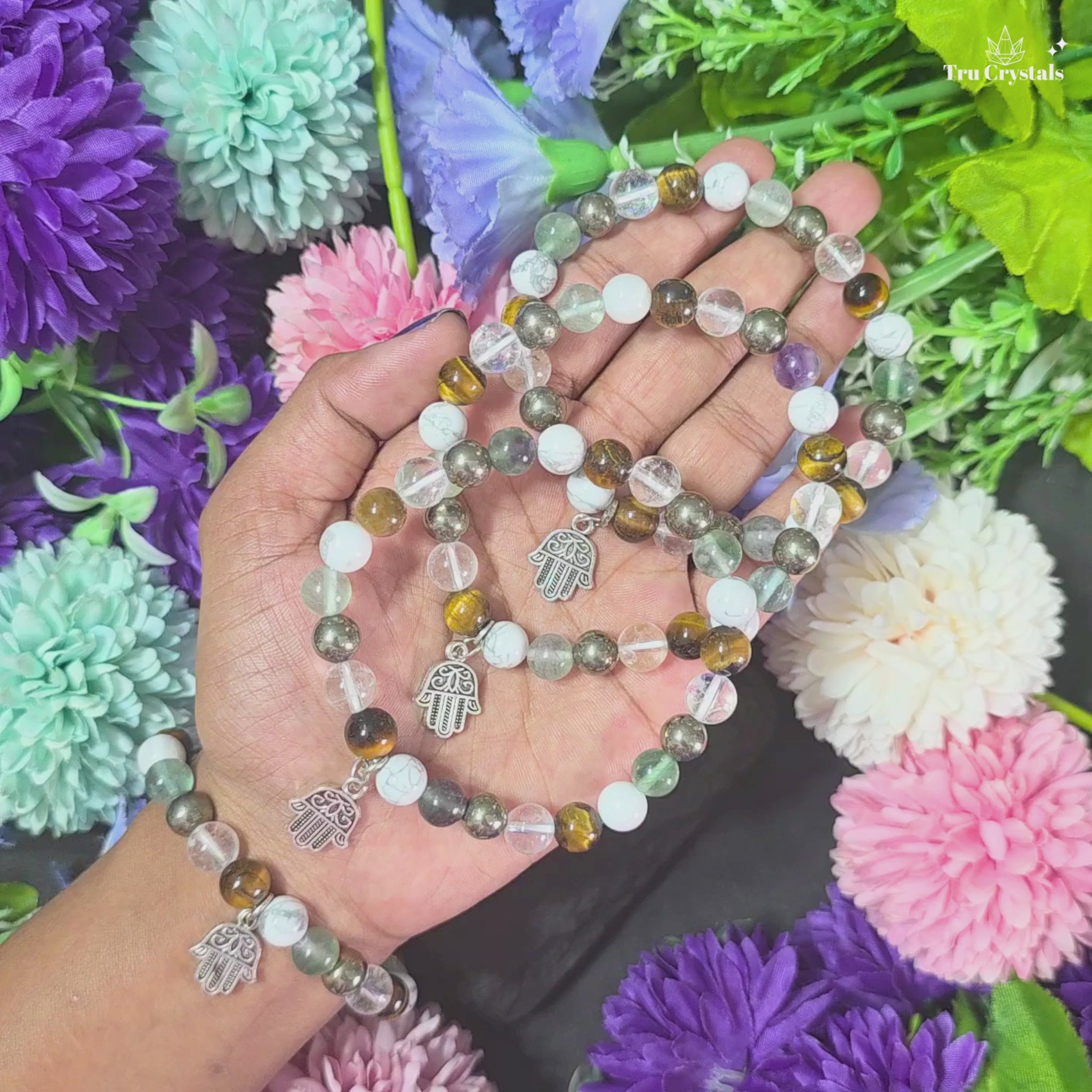 A multicolored student  bracelet featuring Tiger eye , fluorite , howlite,clear quartz and pyrite and a metal charm in the shape of a hand